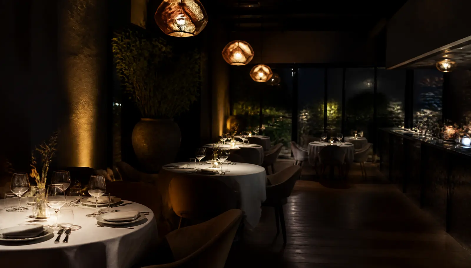 Salle de restaurant le soir, tables dressées sous une lumière chaude